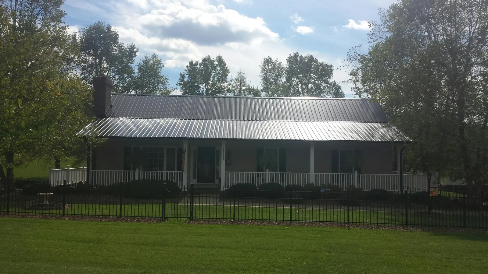 Gray metal roof on a brick ranch with a full width front porch — Gutter Guard Installation work by our crew in Keller